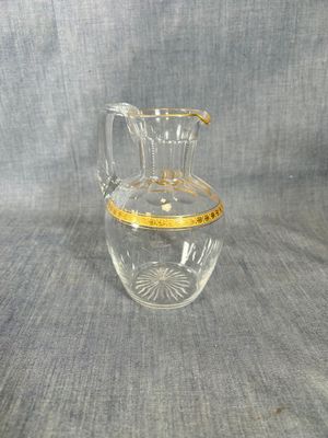 a clear glass pitcher with a gold rim on it