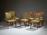 four wooden chairs with green upholstered upholstered cushions in a dark room