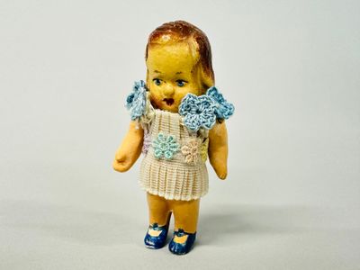 une petite poupée qui porte une robe et des chaussures bleues