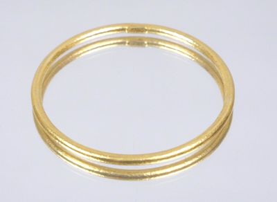 a close up of a gold bang bracelet on a white surface