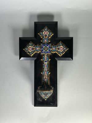 une croix accrochée au mur, avec un vase devant
