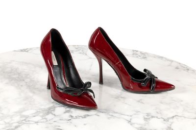 une paire de chaussures à talons hauts rouges posée sur une table en marbre, sur fond blanc