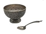 un bol en argent et une cuillère sur fond blanc
