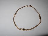 a close up of a gold bracelet on a white surface