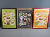 three framed menus of various types of food displayed on a table