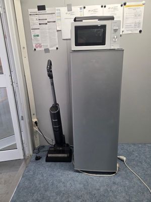 a silver refrigerator and a black vacuum on the floor