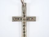 a silver cross that is on a white surface