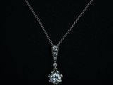 a white gold pendant with a diamond set in the center on a black background