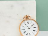 a gold pocket watch sitting on a marble block