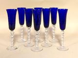 six verres à vin bleus sont alignés sur une surface blanche