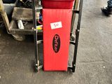 un chariot avec un siège rouge et un sac rouge posé dessus