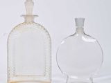 two glass bottles sitting next to each other on a white surface
