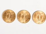 trois pièces d'or sont alignées sur une surface blanche