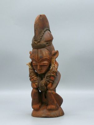 une vieille statue en bois d'un homme avec un chapeau sur la tête