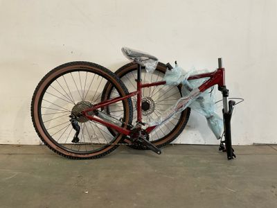 un vélo appuyé contre un mur, sur lequel est posé un sac en plastique