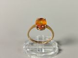 a ring with an orange stone in it on a clear stand