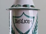 a white and green jar with a green crest on it
