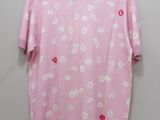 a pink t - shirt with white flowers on it hanging on a hanger