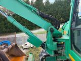 a green excavator that is sitting in the dirt