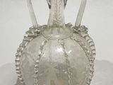 a glass bottle with a handle on a white surface