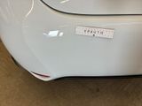 the rear end of a white car with a sticker on it ' s bumper