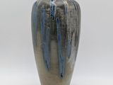 un vase bleu et gris posé sur une surface blanche