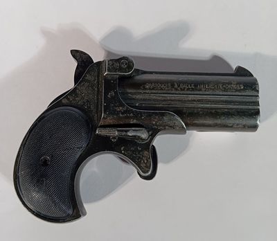un vieux pistolet posé sur une surface blanche, avec une ombre projetée sur le mur