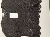 a knitted shawl on a table next to a cup of coffee