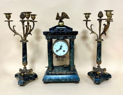 three candles and a clock sitting on a table