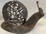 une sculpture représentant un escargot, réalisée à partir de pièces métalliques, posée sur une table