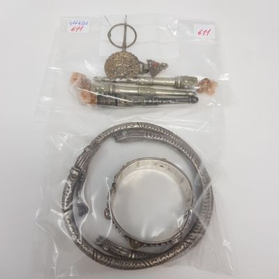 deux bracelets en argent et une paire de ciseaux dans un sac