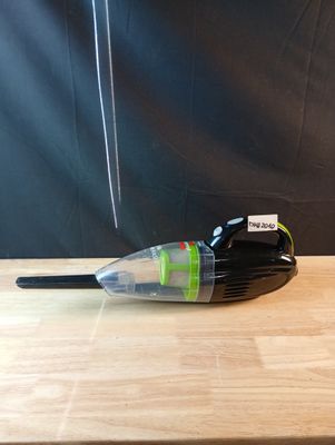 un petit aspirateur noir et vert posé sur une table en bois