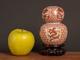 a yellow apple next to a vase on a table