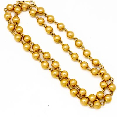 a close up of a gold beaded necklace on a white background