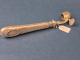 une brosse à dents ancienne en argent posée sur un fond bleu, avec une étiquette de prix