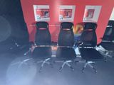 four black office chairs are lined up against a red wall