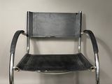 an image of a black leather and chrome chair against a white wall
