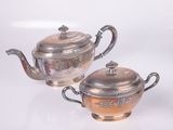 three silver teapots sitting on a white surface