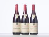 three bottles of red wine are lined up on a table