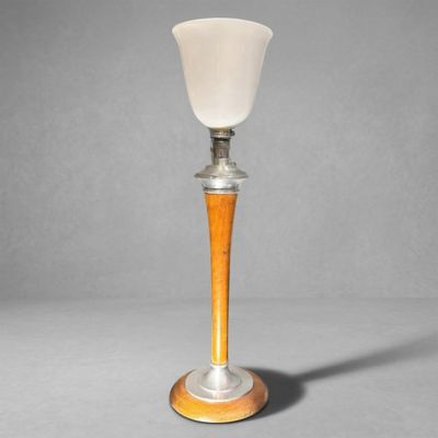 a close up of a lamp on a wooden base with a white glass shade