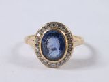 a close up of a ring with a blue stone surrounded by diamonds