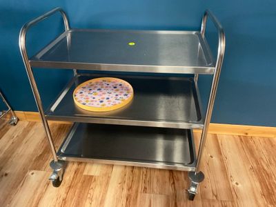 un chariot en métal sur lequel se trouve une pizza, posé sur un parquet