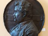 une plaque en bronze représentant un homme moustachu, fixée au mur