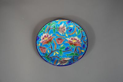 une assiette bleue ornée de fleurs, posée sur un mur