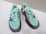 pair of green and pink running shoes sitting on a white surface