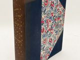 an old book sitting on top of a white surface with a blue cover