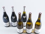 six bottles of wine are lined up in a row on a white surface