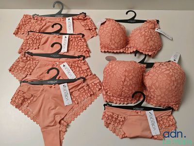 Plusieurs soutiens-gorge et culottes sont exposés sur une table, suspendus à des cintres