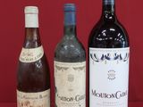 three bottles of wine are lined up on a red surface