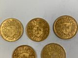 quatre types différents de pièces d'or reposant sur une surface blanche